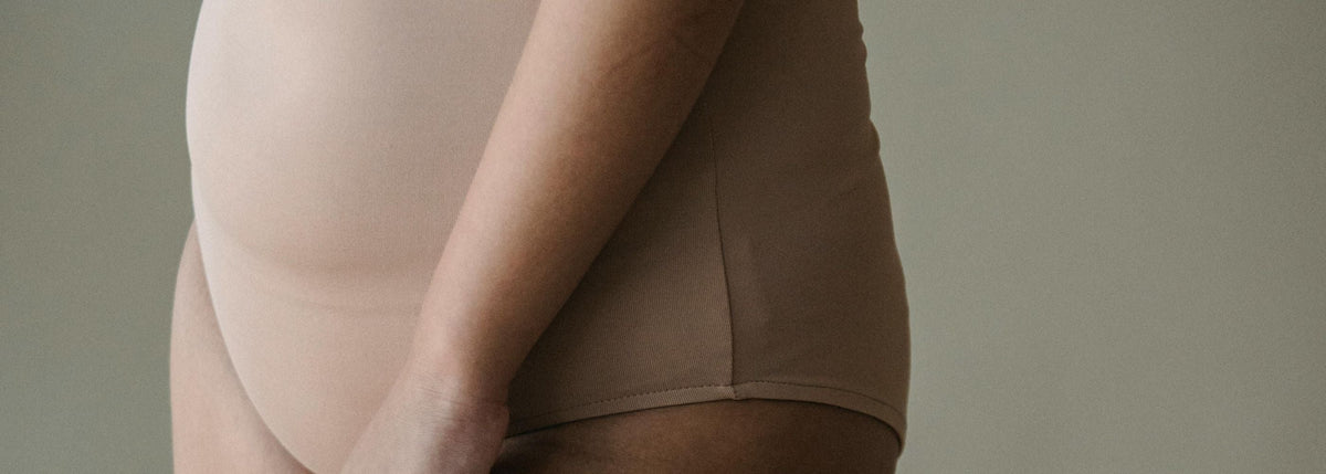 Une femme avec le ventre légèrement gonflé, pour illustrer les compléments alimentaires pour la digestion