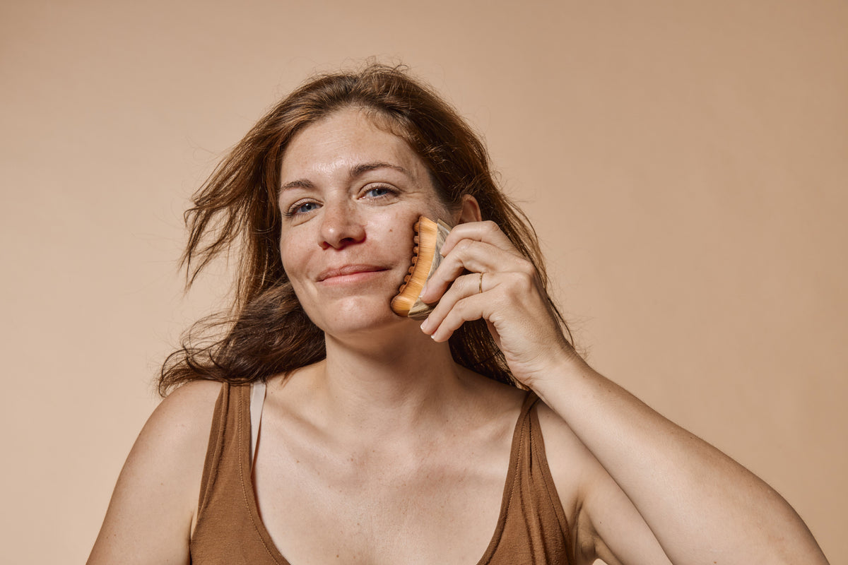 Une femme souriante se masse le visage avec l'un de nos accessoires MiYé