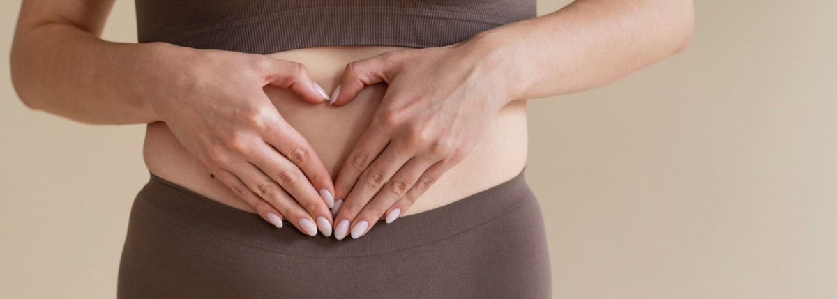Une femme fait un coeur avec ses mains sur son ventre, pour illustrer les règles douloureuses