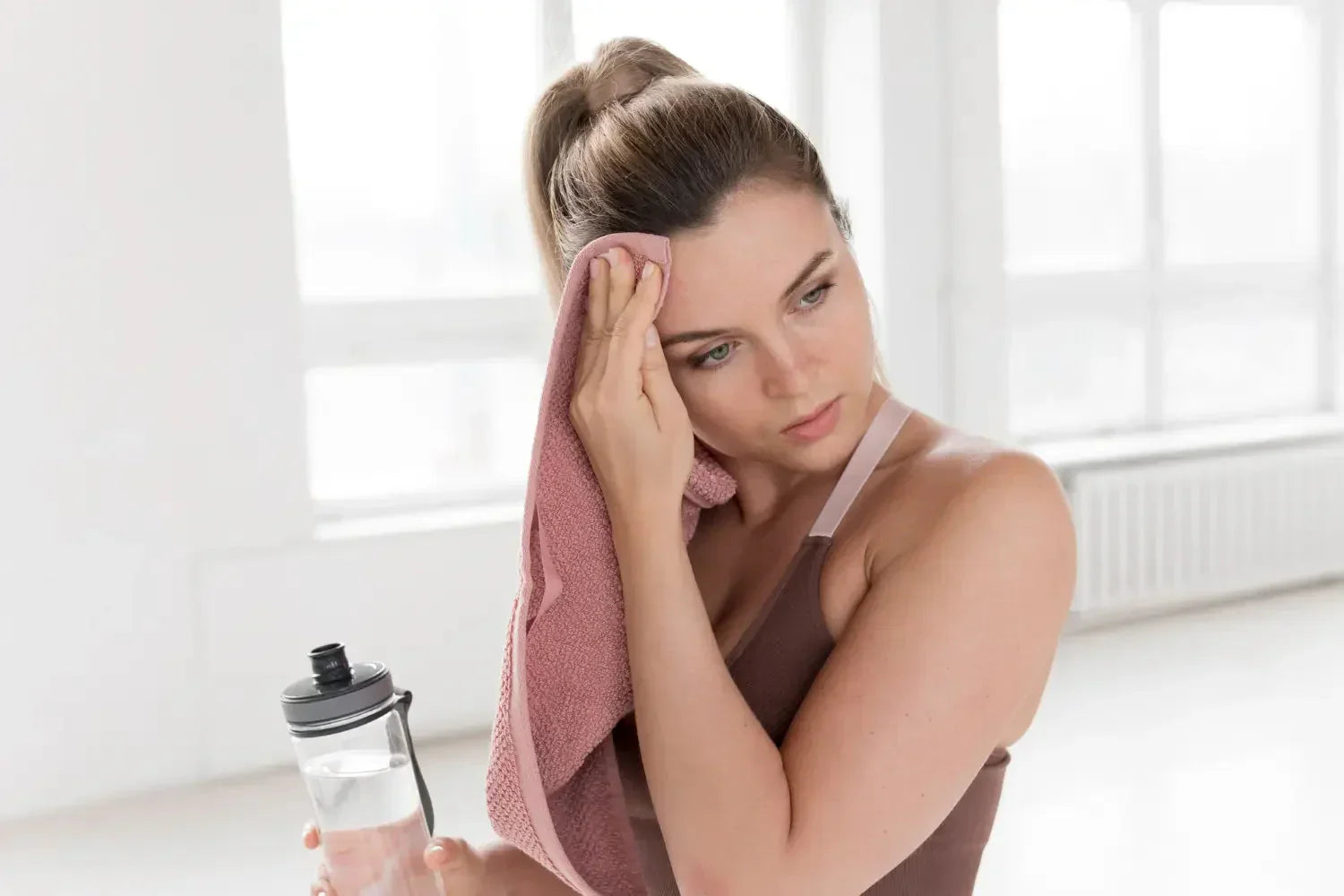 Femme en tenue de sport qui s'essuie le front après l'effort